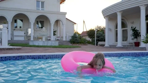 Beautiful Little girl swimming on Inflatable pink ring in pool, Summer vacation Stock Footage