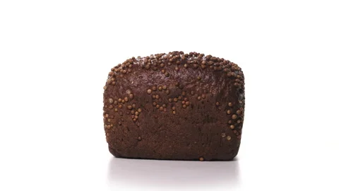 Beautiful loaf of black bread with sprinkles spinn on white background. Fresh Stock Footage 148508930