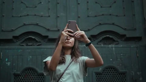 Beautiful long-haired brunette making photo in front of a large carved door Stock Footage 139350909
