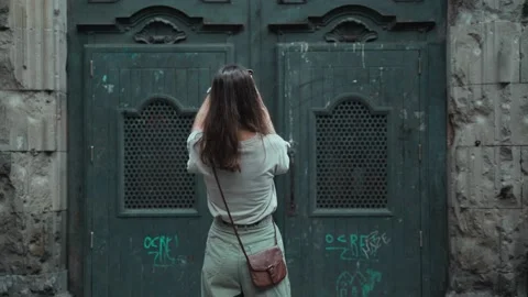 Beautiful long-haired brunette making photo of a large carved door. Young Stock Footage 139441852