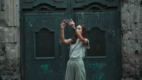 Beautiful long-haired brunette making photo in front of a large carved door Stock Footage 139442081