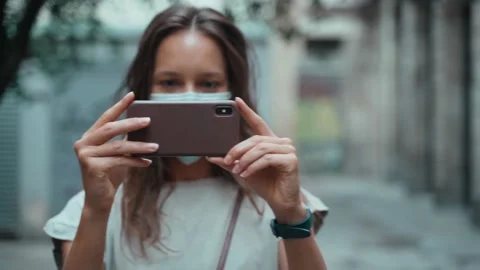Beautiful long-haired brunette in protective mask makes selfie on the square Stock Footage 139350872