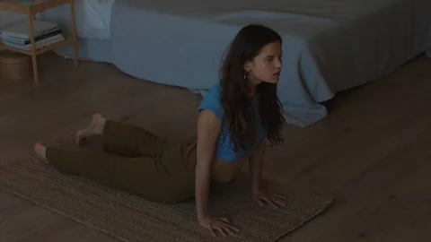 Beautiful long-haired girl practicing yoga indoors dark interior background 4k  Stock Footage 106434090
