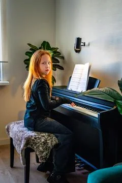 Beautiful long-haired red-haired teenage girl  plays the piano Stock Photos