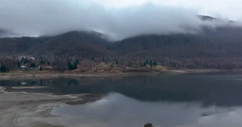 Beautiful low to the ground drone shot a small village and a lake. Foggy morning Stock Footage 174444997