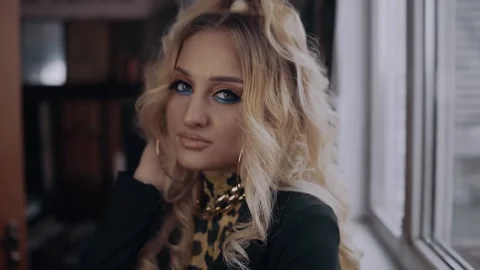 The beautiful make-up and curly blonde walks her hands in her hair and then Stock Footage 157683409