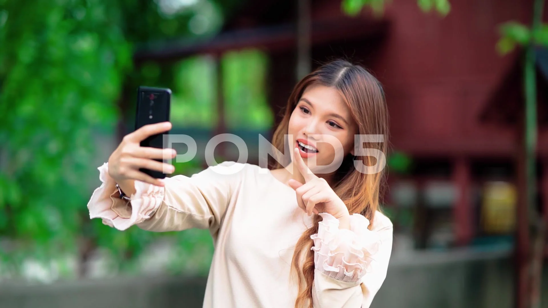 beautiful malay girl using smart phone with malay house in the background