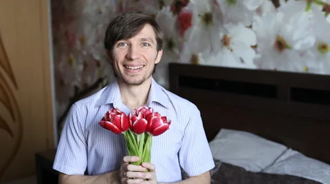 Beautiful man with affection presents flowers to the camera - the tulips. Stock Footage 60054371