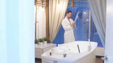 Beautiful man is standing at the panoramic window in a luxury Spa waiting for Stock Photos