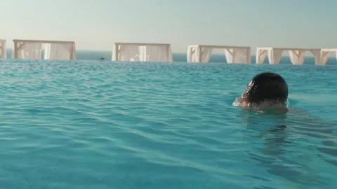Beautiful man swimming in the pool, overlooking the sea and mountains Stock Footage 145080974