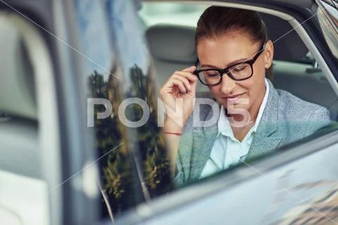 Beautiful middle aged business woman adjusting her eyeglasses while sitting on Stock Photos