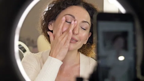 Beautiful middle aged woman demonstrates the application of a moisturizing and Stock Footage 168973553