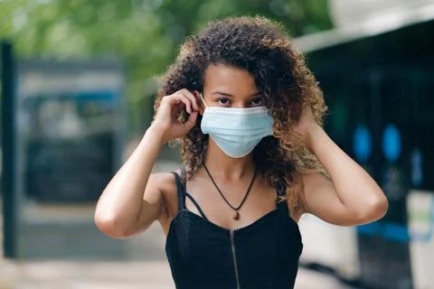Beautiful mixed race young female wearing mask to prevent from virus contamin Stock Photos