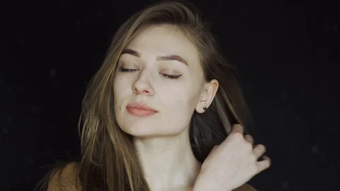 A beautiful model girl straightens her hair and looks into the camera. She Stock Footage 88826853