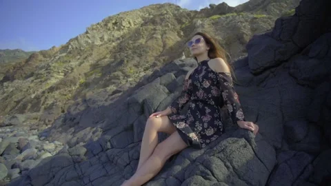 A beautiful model with glasses poses on a large stone. Stock Footage 221274708