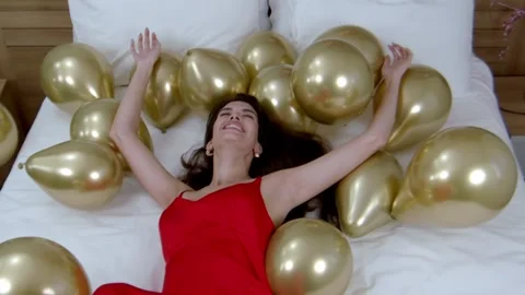 Beautiful model gracefully descends onto collection of balloons. Slow-mo Stock Footage 263275900