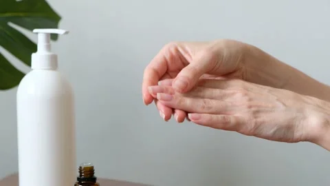 Beautiful model hands applying cosmetic cream oil treatment on her hand and Stock Footage 200116840