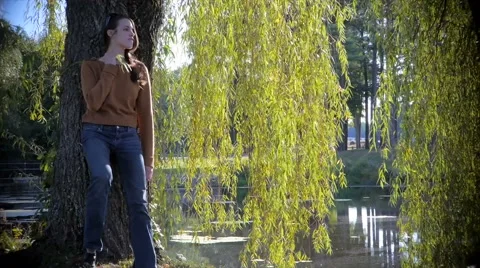 Beautiful model leans on tree and walks toward lake Stock Footage 40294957