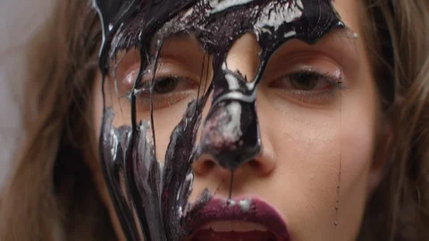 Beautiful model with liquid black paint oil leaking on her face on gray backg Stock Footage 104958480
