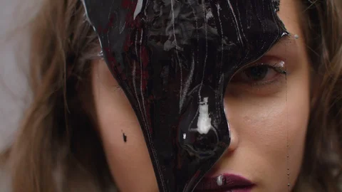 Beautiful model with liquid black paint oil leaking on her face on gray backg Stock Footage 106362218