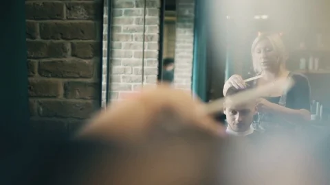 Beautiful model man is sitting in chair at barber shop. Female hairdresser is Stock Footage 93752007