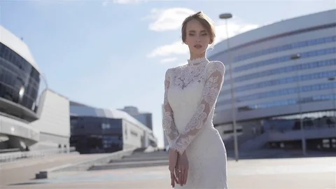 Beautiful model posing in elegant wedding dress standing in business city center Stock Footage 87011150