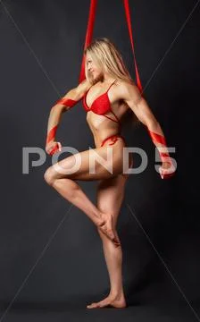A beautiful model in red bikini marching to the left with red ribbons wound roun Stock Photos