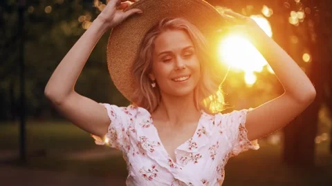 A beautiful model stands and wears a hat outside in the park during a walk Stock Footage 242597975