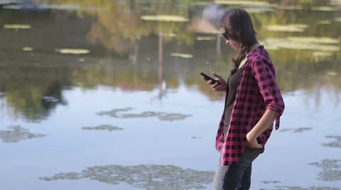Beautiful model using a smart phone at lakeshore Stock Footage 34510534