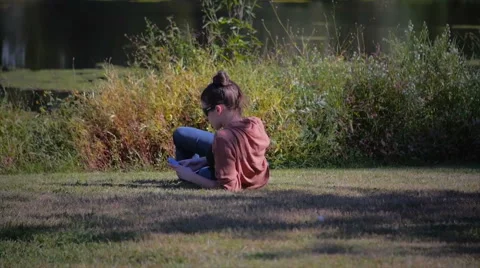Beautiful model using smartphone sitting near a lake Stock Footage 40293542