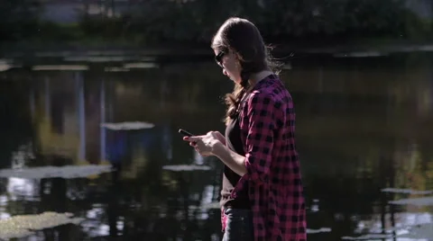 Beautiful model using smartphone standing in front of lake Stock Footage 40295074