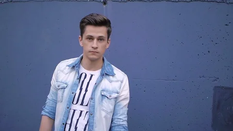 Beautiful model young guy poses by the wall Stock Footage 72833273