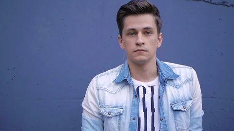 Beautiful model young guy poses by the wall Stock Footage 72833467