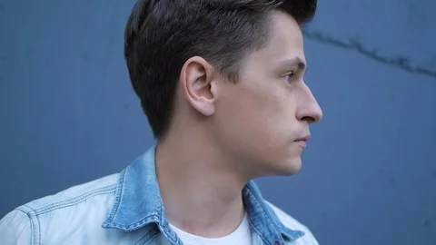 Beautiful model young guy poses by the wall Stock Footage 72833556