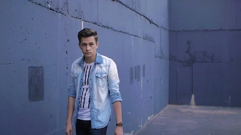 Beautiful model young guy poses by the wall Stock Footage 72833675