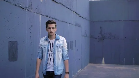 Beautiful model young guy poses by the wall Stock Footage 72833813