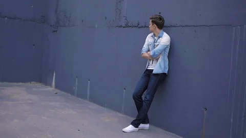Beautiful model young guy poses by the wall Stock Footage 72833900