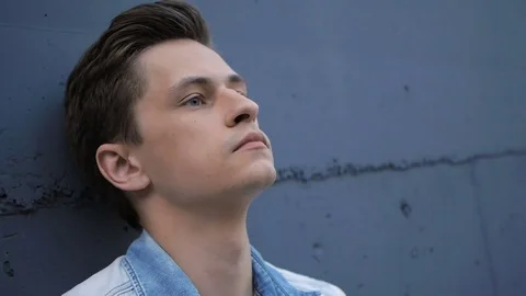 Beautiful model young guy poses by the wall Stock Footage 72834102