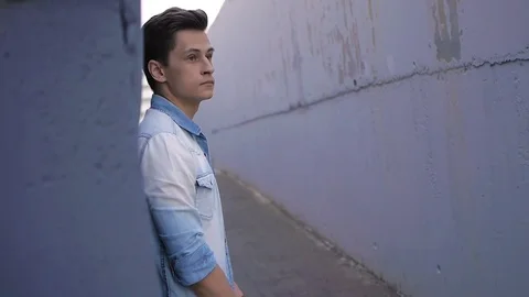 Beautiful model young guy poses by the wall Stock Footage 72834154