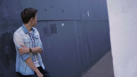 Beautiful model young guy poses by the wall Stock Footage 72834250