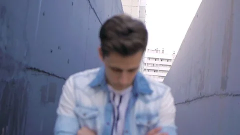 Beautiful model young guy poses by the wall Stock Footage 72834659