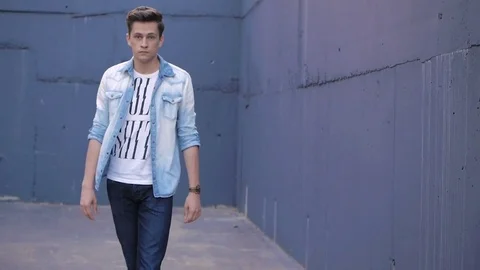 Beautiful model young guy poses by the wall Stock Footage 72834726