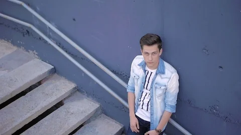 Beautiful model young guy poses by the wall Stock Footage 72835065