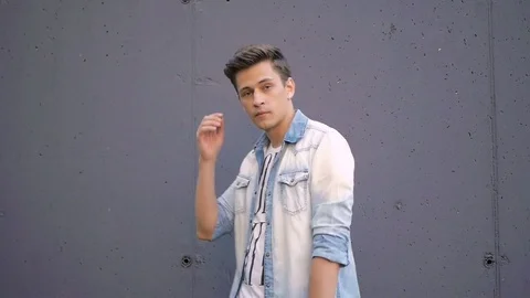 Beautiful model young guy poses by the wall Video stock 72836951