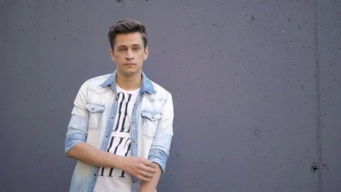 Beautiful model young guy poses by the wall Video stock 72837644