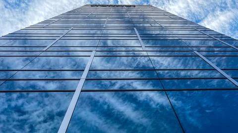 Beautiful modern tall tower with clouds in financial district. Windows skylin Ilustración de archivo