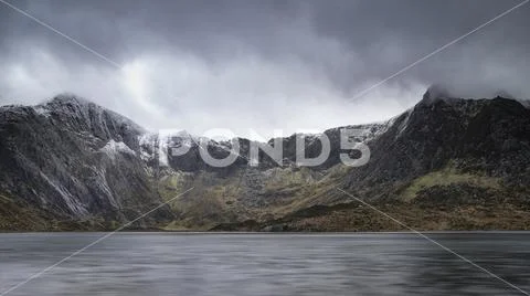 Beautiful moody Winter landscape image of Llyn Idwal and snowcapped Glyders M Stock Photos