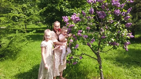 Beautiful mother with two daughters posing in the summer park Stock-Footage 132157373