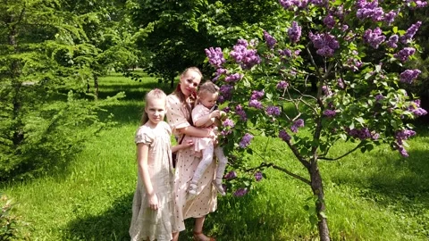 Beautiful mother with two daughters posing in the summer garden Video stock 132312113