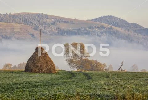 Beautiful mountain landscape with haysatck in the foreground and fog in the b Stock Photos